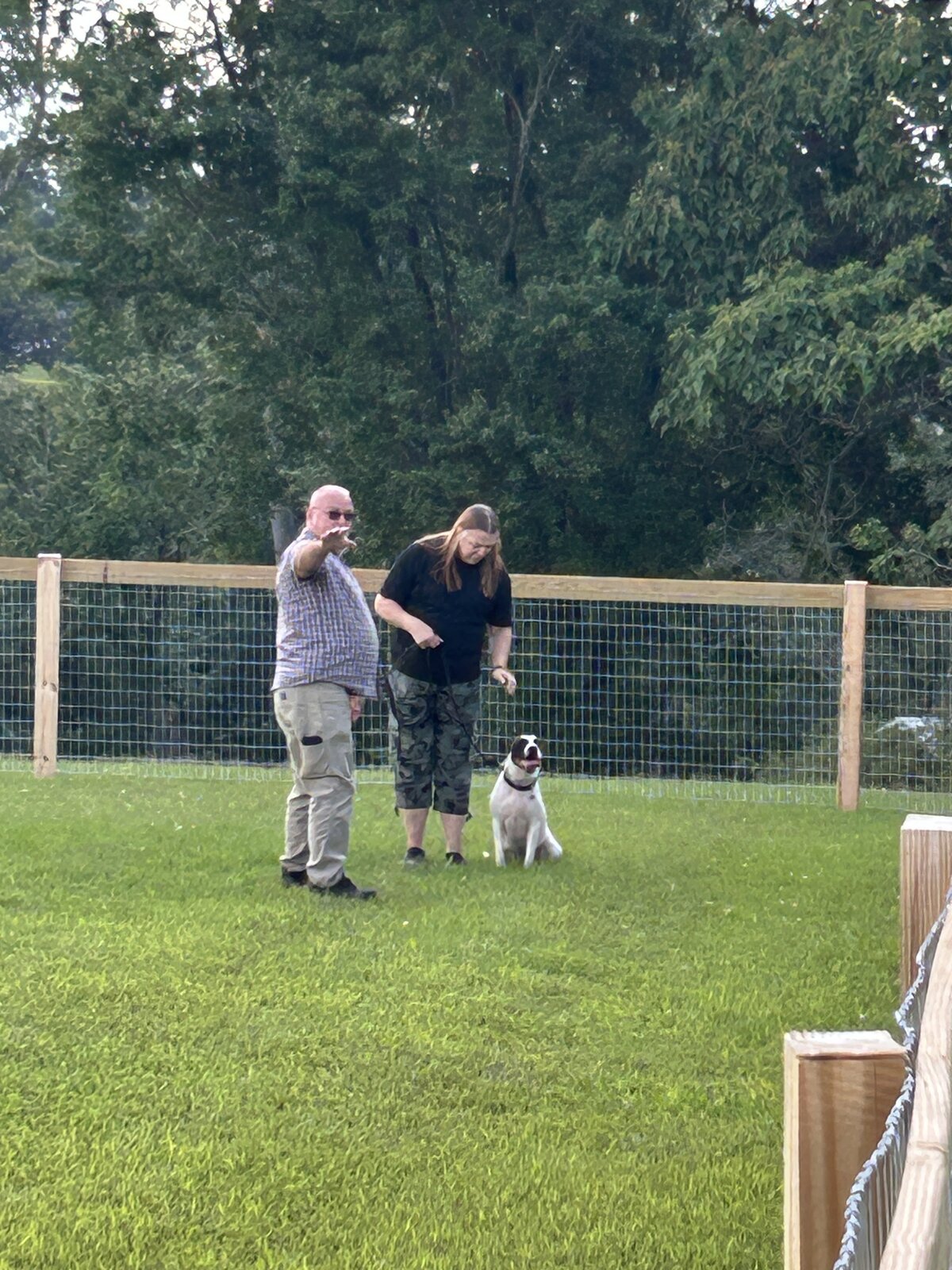 Trainers standing with a dog near the training area fence