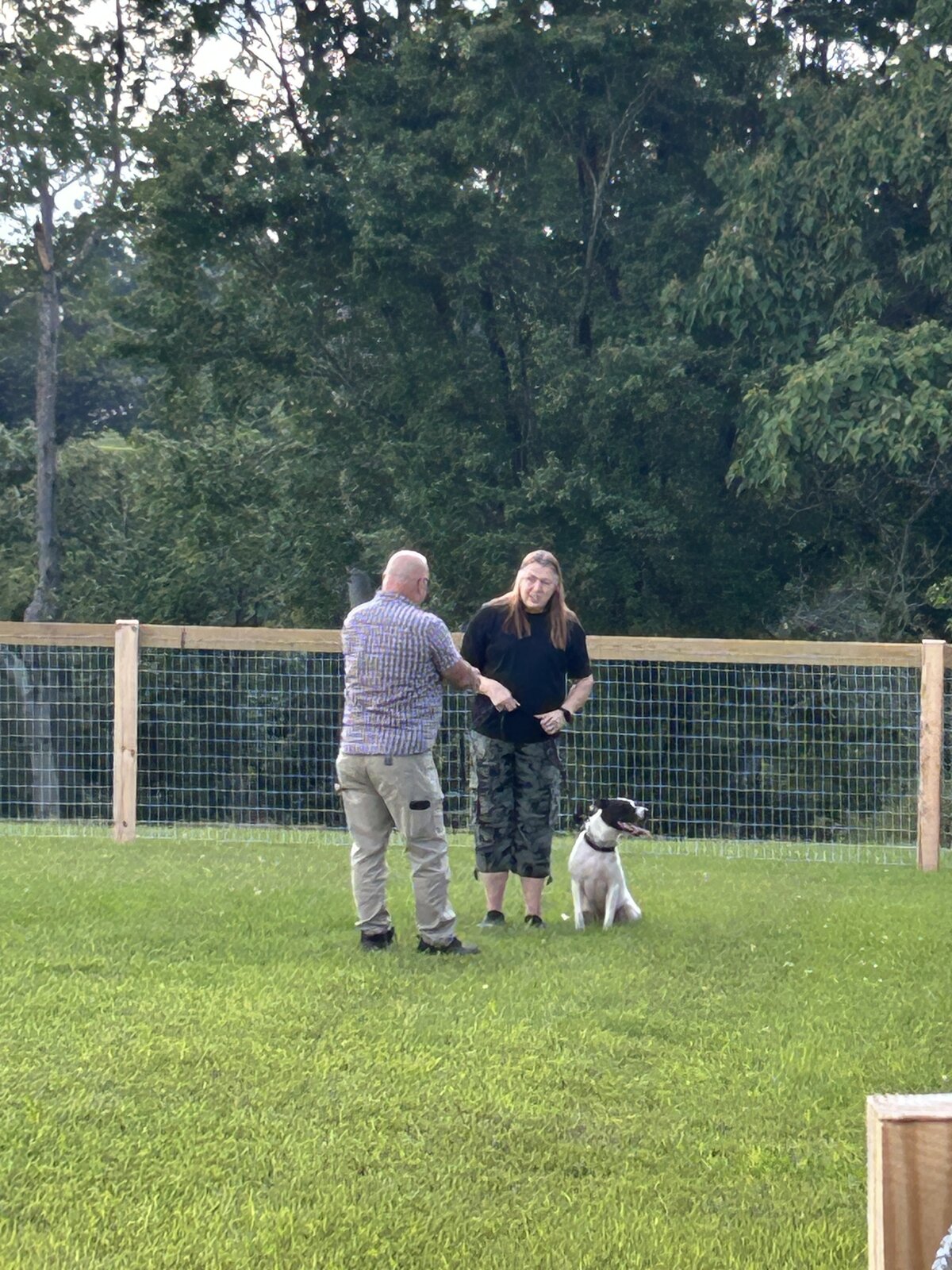 Trainers and dog walking along the training area fence line